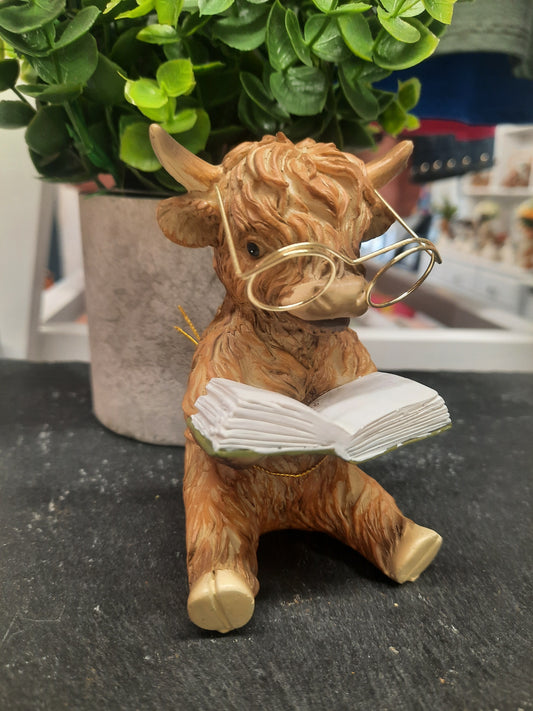 Highland Cow Reading a Book with Glasses...